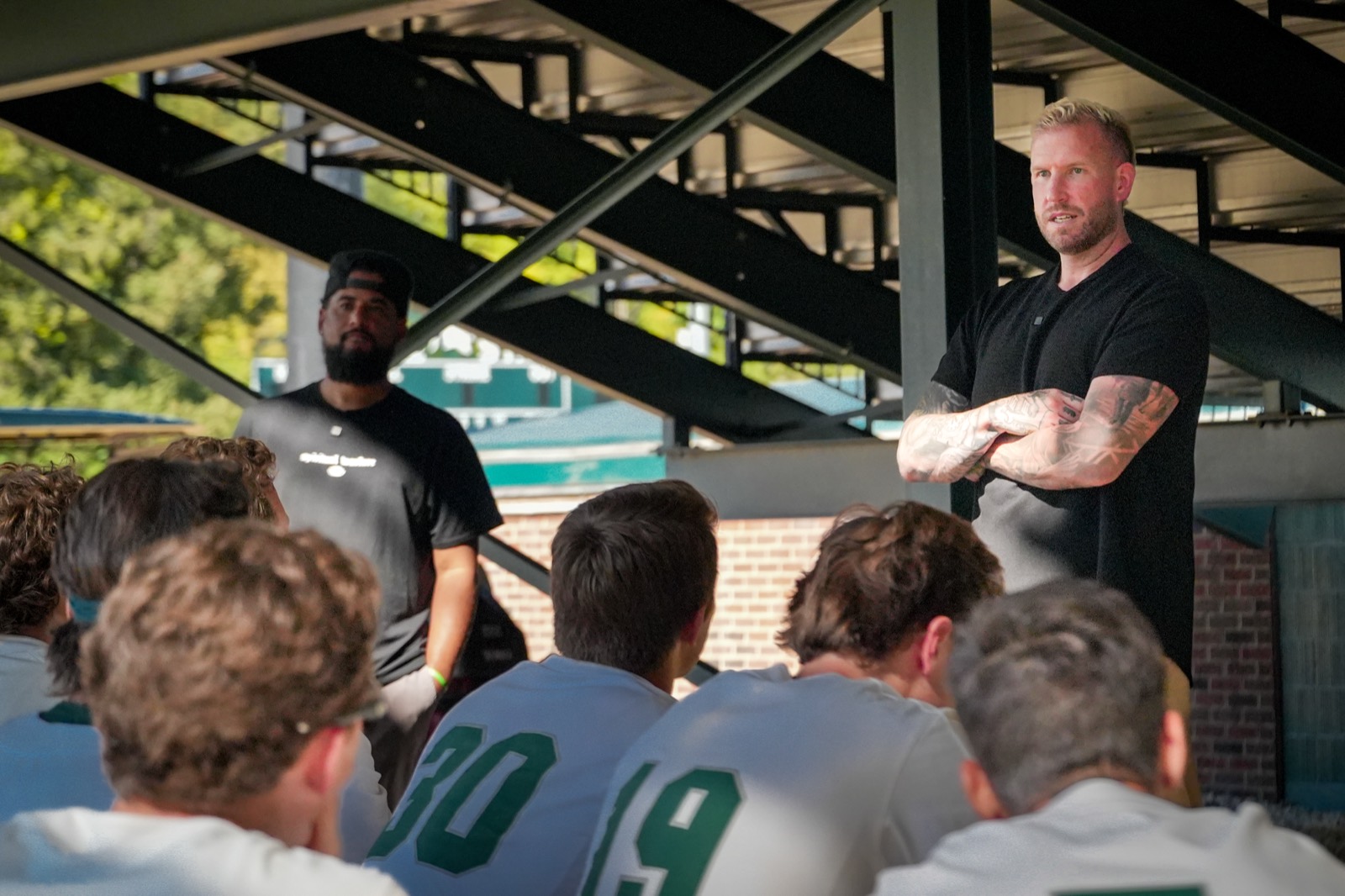 The Under The Brim team speaking with a college baseball team in the dugout